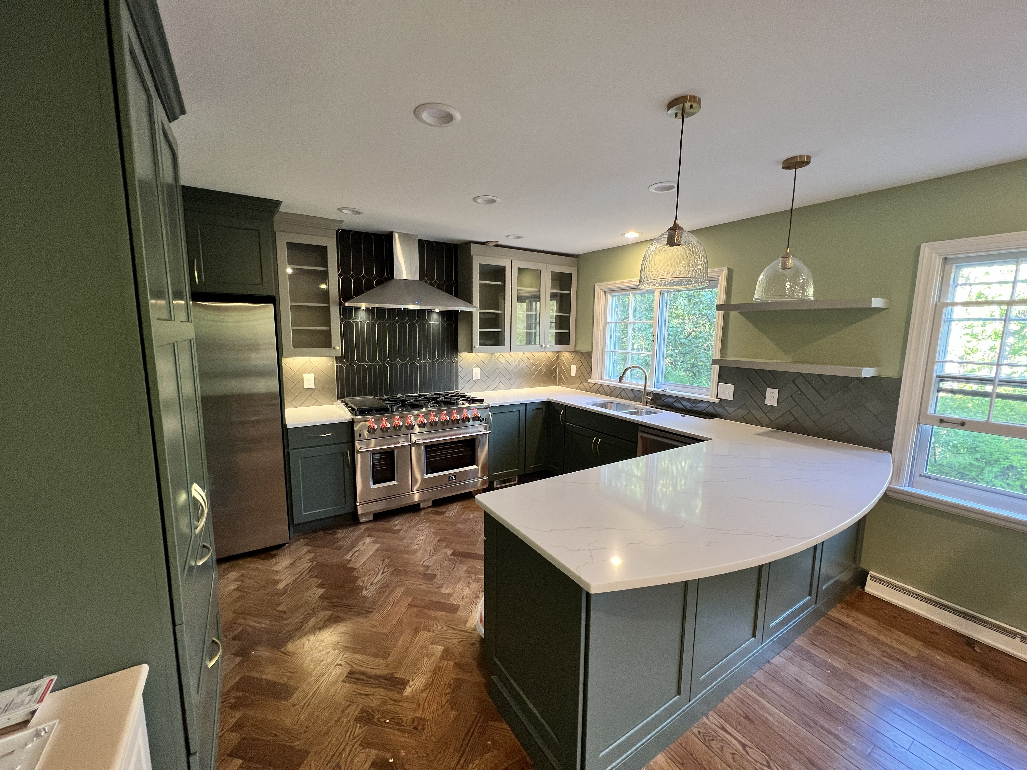 Green shaker kitchen with quartz waterfall peninsula by Resolute Construction and Remodel